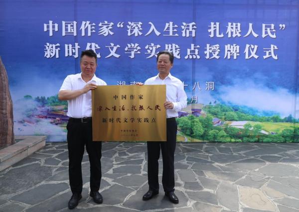 Qiu Huadong, member of the presidium and secretary of the Secretariat of the Chinese Writers Association, awarded Chinese writers a license for the new era of literary practice point of "going deep into life and rooting in the people", and Guo Zhenggui, secretary of the Xiangxi Prefecture Party Committee, took the license. Photography: Wang Jiguo