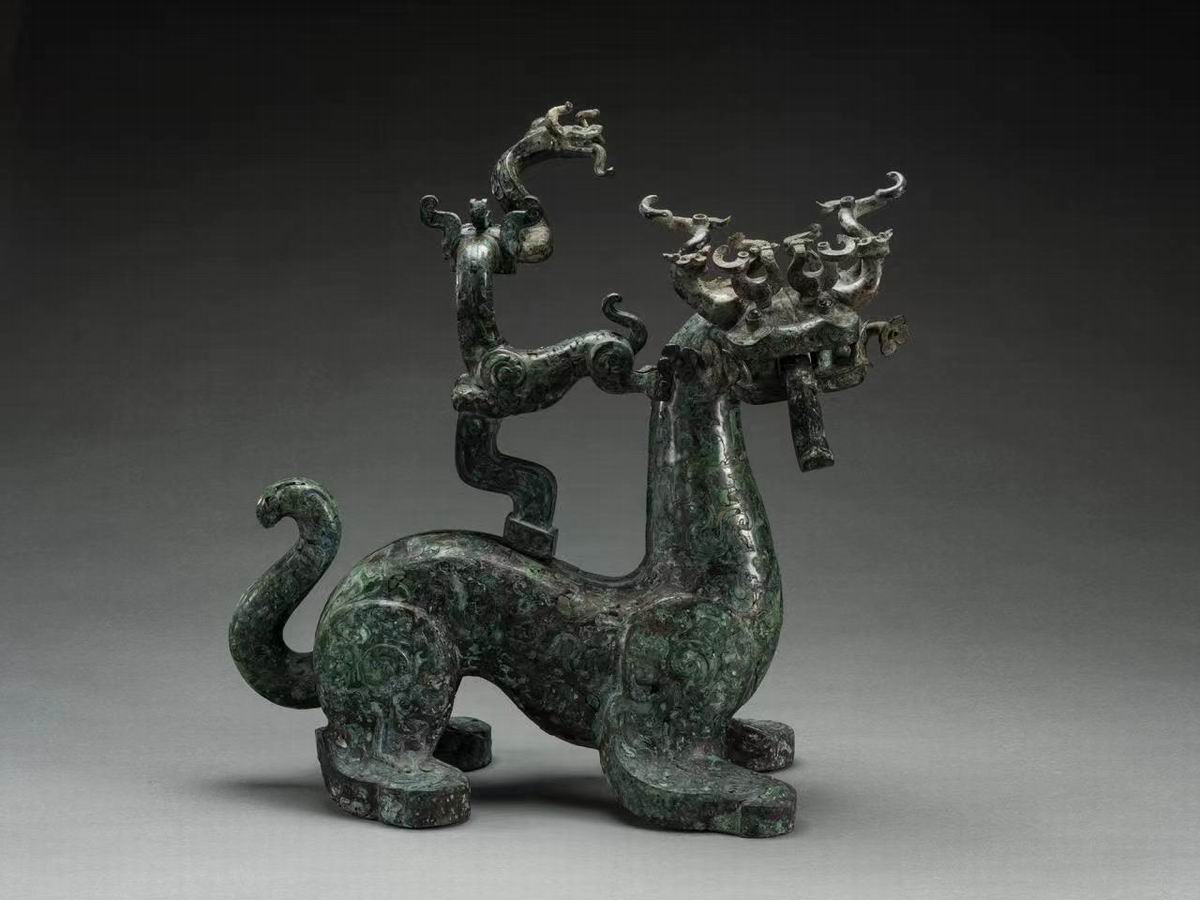 Inlaid turquoise mythical beasts in the late Spring and Autumn Period (570 BC - 476 BC) with a total height of 48.0 cm, a length of 47.0 cm, and a width of 27.0 cm. Unearthed in 1990 in Xujialing, Xichuan, Henan Provincial Institute of Cultural Relics and Archaeology has a dragon head, tiger neck, and tiger body. Tiger tail, turtle feet. The dragon opened its mouth and stuck out its tongue, and there were six more dragons on the dragon's head. There is a seat on its back, and there is a Benz-shaped beast on the seat, with a curly tail and the tail of a snake-shaped dragon in its mouth. The snake-shaped dragon holds its head high, with three horns on its head, sticks its tongue out, and bows. The body of the beast is inlaid with turquoise, with patterns of dragon, phoenix, tiger, cloud pattern, vortex pattern and so on. The images of dragons, phoenixes and tigers are vivid. The beasts are unique in shape and exquisite in production.