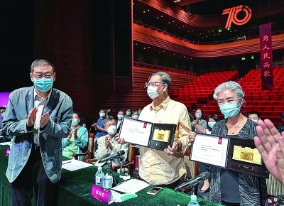 On June 12, veteran artists Guo Qihong (middle) and Lv Zhong (right) of Beijing People's Art Theater were awarded honorary plaques at the symposium. Xinhua News Agency