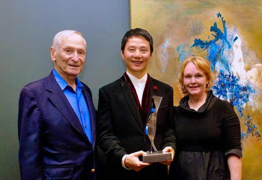 Shen Wei receives the Lifetime Achievement Award with his paintings behind him.